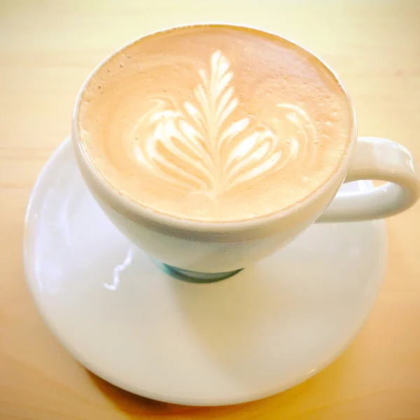Latte art kávy na dřevěný stůl s efekt retro filtru — Stock fotografie