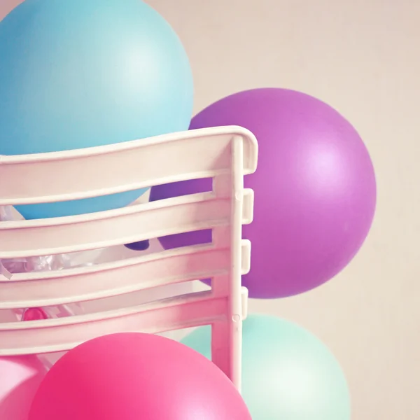 Colorful balloons on chair with retro filter effect — Stock Photo, Image