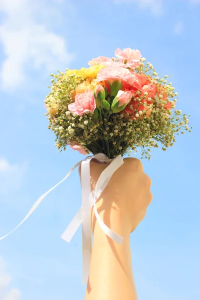 Ramo de flores en mano y cielo azul — Foto de Stock