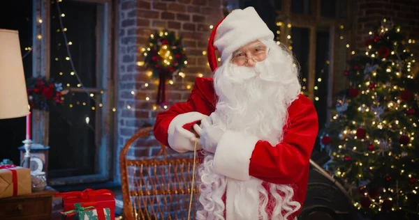 Derékig érő portré a boldog idős ember Santa Clause jelmez táska ajándékokat, miközben időt tölt otthon. Ünnepi koncepció — Stock Fotó