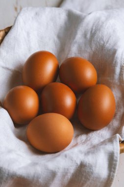 Keten havluyla kaplanmış hasır sepetteki tavuk yumurtaları...