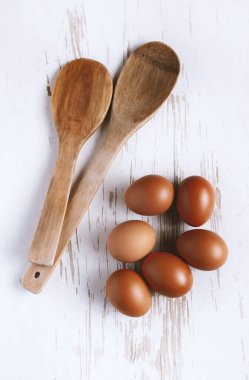 Beyaz ahşap arka planda yumurta ve tahta kaşıklar