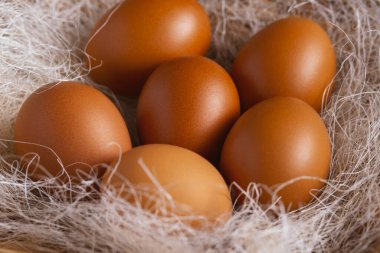 Hasır bir sepette samanla kahverengi tavuk yumurtası