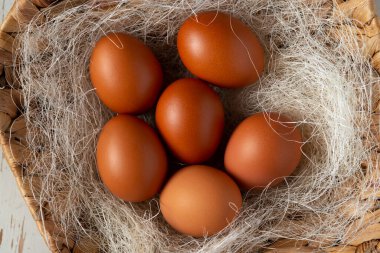 Hasır bir sepette samanla kahverengi tavuk yumurtası