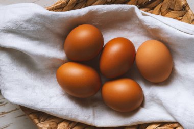 Keten havluyla kaplanmış hasır sepetteki tavuk yumurtaları...