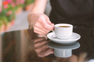Kahve dükkanının arka planında, ahşap sehpanın üzerinde beyaz kahve fincanı.
