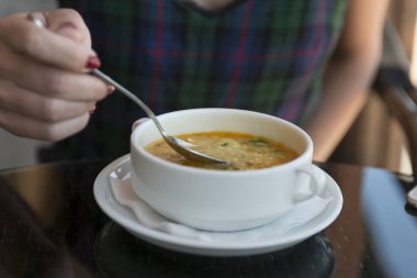 Restoranda tavuk ya da sebze çorbası içen kız. Lokantada çorba içerken kaşık tutan bir kadın.
