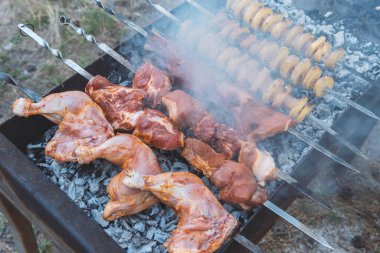 Domuz eti, tavuk eti ve patatesler dumandaki barbeküde şiş üstünde