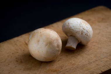 Şampiyon mantarları siyah arka planda tahta bir tahtada