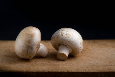 Şampiyon mantarları siyah arka planda tahta bir tahtada