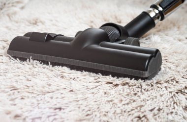 Bir kalın kazık beyaz carpet.still hayat koyu tonu vakumlama sırasında kullanılan modern elektrikli süpürge Başkanı yakın çekim.