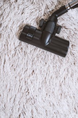 Bir kalın kazık beyaz carpet.still hayat koyu tonu vakumlama sırasında kullanılan modern elektrikli süpürge Başkanı yakın çekim.