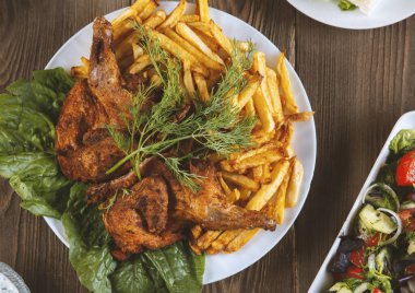 Ahşap bir masada kızarmış tavuk ve patates kızartması.
