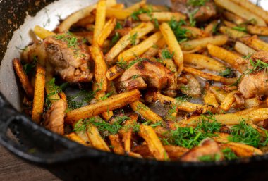 Demir bir tavada kızarmış et ve patates.