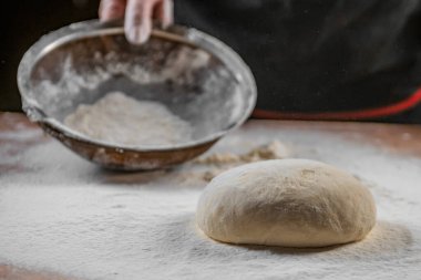Hamur yoğurma fırını. Aşçı ahşap masada turta pişirmek için hamur yapıyor. İşlem hazırlığı ev yapımı hamur işi. Makarna, ekmek, spagetti, khachapuri, yemek konsepti.