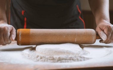 Pizza hazırlamak için hamur yoğuruyorum. Aşçı ahşap masada turta pişirmek için hamur yapıyor. İşlem hazırlığı ev yapımı hamur işi. Makarna, ekmek, spagetti, khachapuri, yemek konsepti.