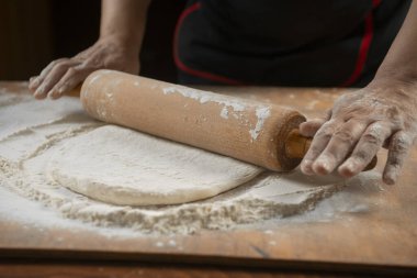 Pizza hazırlamak için hamur yoğuruyorum. Aşçı ahşap masada turta pişirmek için hamur yapıyor. İşlem hazırlığı ev yapımı hamur işi. Makarna, ekmek, spagetti, khachapuri, yemek konsepti.