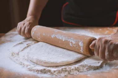 Pizza hazırlamak için hamur yoğuruyorum. Aşçı ahşap masada turta pişirmek için hamur yapıyor. İşlem hazırlığı ev yapımı hamur işi. Makarna, ekmek, spagetti, khachapuri, yemek konsepti.
