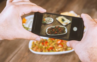 Yemeklerin akıllı telefon fotoğrafı. İnsan elleri geleneksel doğu yemeklerini telefonla çekiyor. Öğle ya da akşam yemeği. Sosyal medya ve blog için. Sağlıklı yemek.