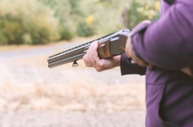 Erkek avcı av tüfeğiyle avlanmaya hazır. Avcı tüfeğini tutuyor..