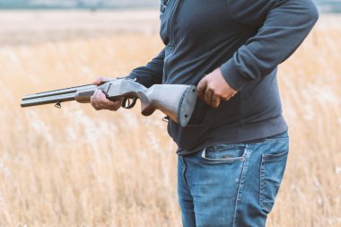 Erkek avcı av tüfeğiyle avlanmaya hazır. Avcı tüfeğini tutuyor..