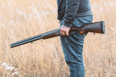 Erkek avcı av tüfeğiyle avlanmaya hazır. Avcı tüfeğini tutuyor..