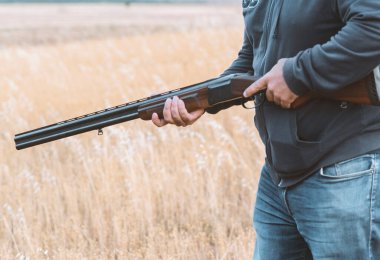 Erkek avcı av tüfeğiyle avlanmaya hazır. Avcı tüfeğini tutuyor..