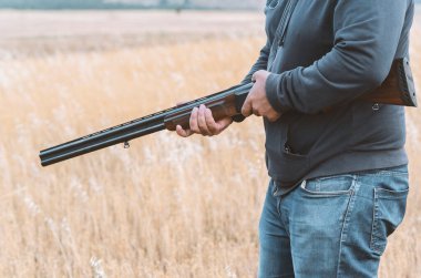 Erkek avcı av tüfeğiyle avlanmaya hazır. Avcı tüfeğini tutuyor..