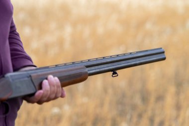 Erkek avcı av tüfeğiyle avlanmaya hazır. Avcı tüfeğini tutuyor..