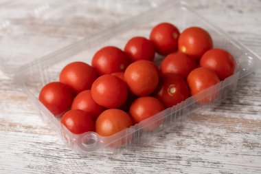 Tahta masadaki plastik kaplarda kiraz domatesleri.