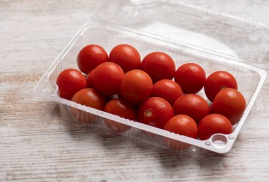 Tahta masadaki plastik kaplarda kiraz domatesleri.