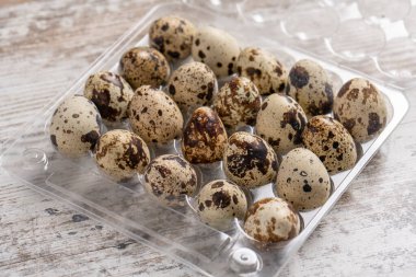 Tahta bir masada plastik kaplarda bıldırcın yumurtaları.