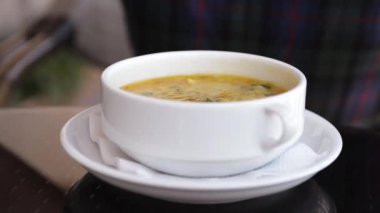 Blonde woman eats her soup with vegetables