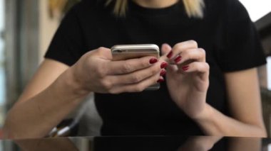  Blonde woman sitting and using her phone