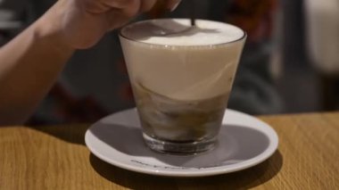 Woman sitting in a coffee house, mixes coffee with a spoon