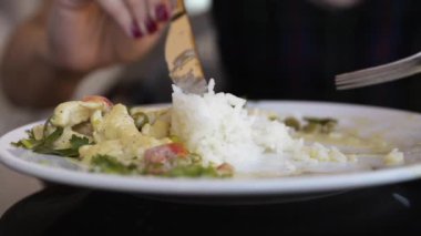 Girl eats chicken meat with beans and rice