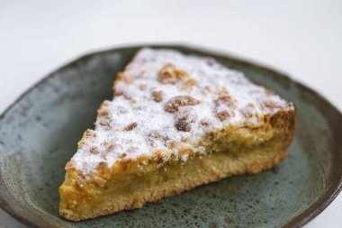 Beyaz ahşap zemin üzerinde seramik tabakta bir parça turta..