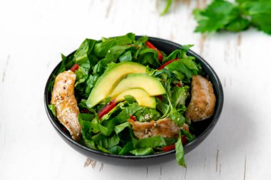 Siyah kasede avokadolu tavuk salatası. Sağlıklı yemek.