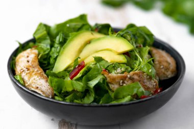Sağlıklı sebze salatası, kızarmış tavuk, avokado, biber ve beyaz tabakta yaprak salatası..