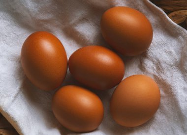 Keten havluyla kaplanmış hasır sepetteki tavuk yumurtaları...