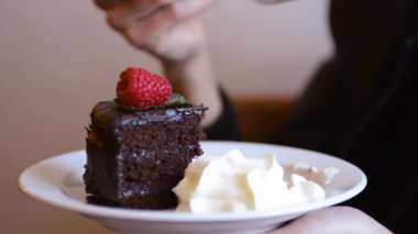 Woman eats a chocolate cake with extra cream