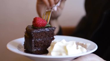Woman eats a chocolate cake with extra cream