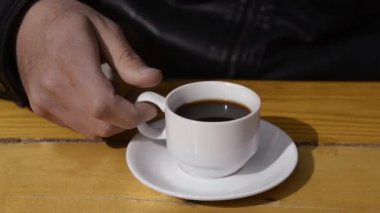 Man drinks a cup of strong coffee in cafe .