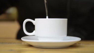 Mixing a cup of coffee with a spoon