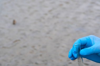 Analiz için nehirden örnek su. Bir test tüpü tutan eldiven. Ekoloji konsepti.