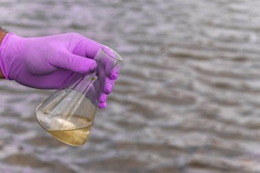 Analiz için nehirden örnek su. Bir test tüpü tutan eldiven. Ekoloji konsepti.