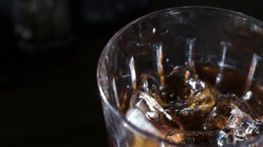 Man fills the glass of ice with cola .