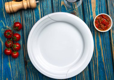 Eski püskü tahtaların, tuz, biber, domates, sos ve bir bardak kırmızı şarabın ahşap arka planında boş bir tabak. Reklam panoları, web sitesi, reklamlar, restoranlar ve kafeler için arka plan. Yukarıya bak