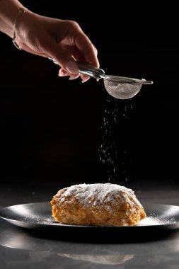 Siyah arka planda krema şekerli Napolyon keki. Napolyon kekini pudra şekeriyle süslemek.