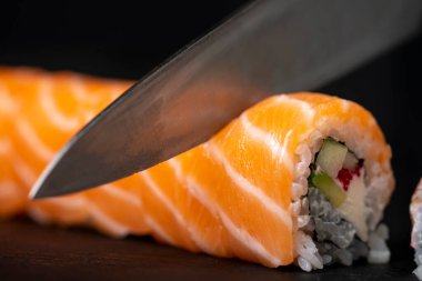 Suşi evde yapılıyor, avokado ve somon ile rulo kesiliyor, ev yapımı suşi, seçici odaklı.